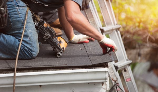 roofers installing a new roof on residential home. weatherlock material and brown asphalt roofing shingles